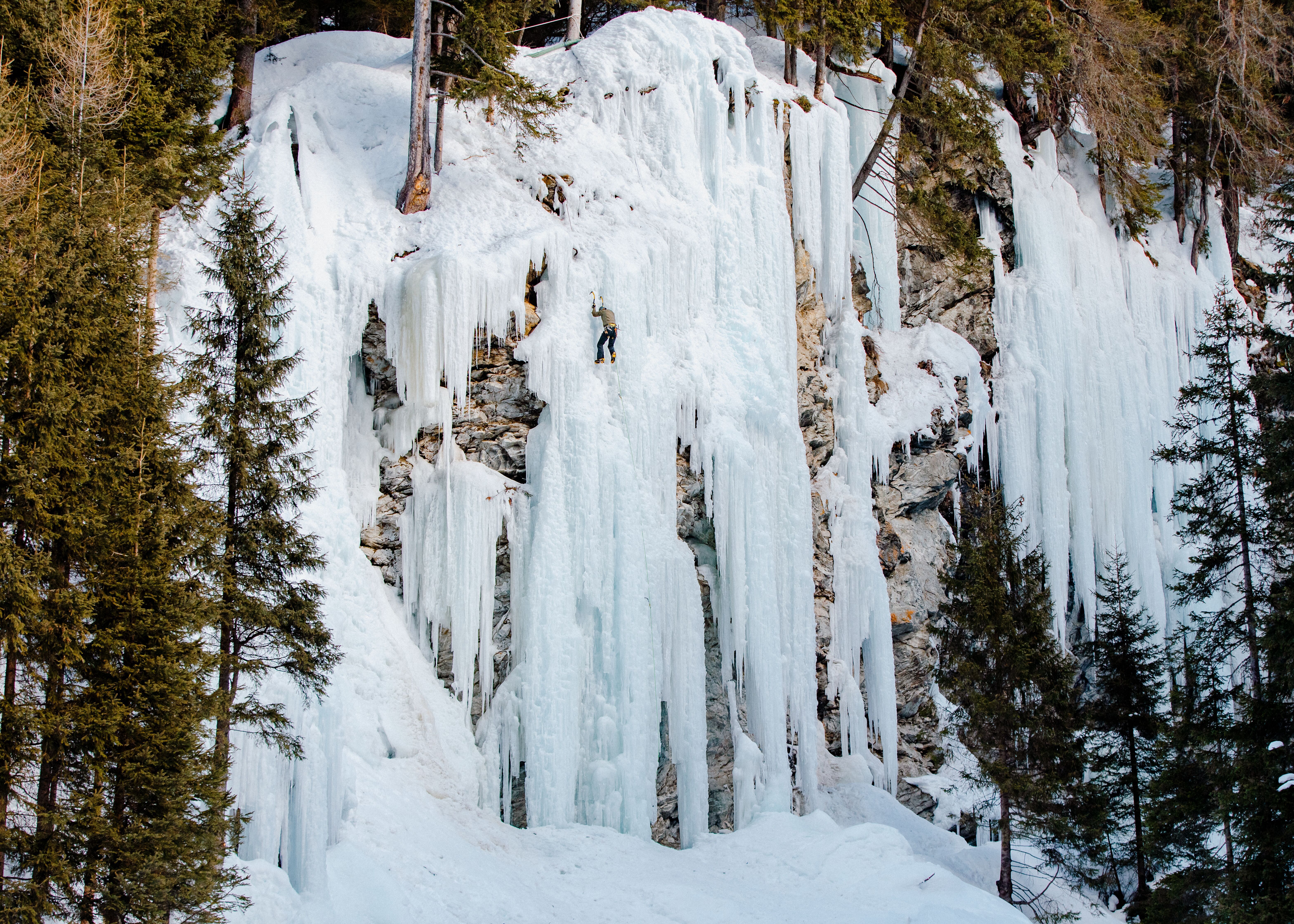 Eiskletterer klettert auf einem zugefrorenen Wasserfall